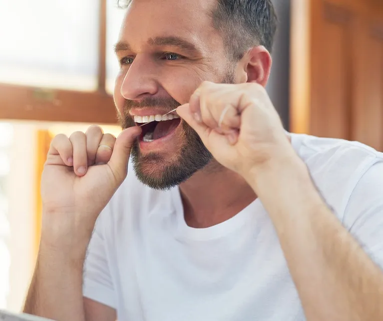 Male flossing his teeth in the mirror